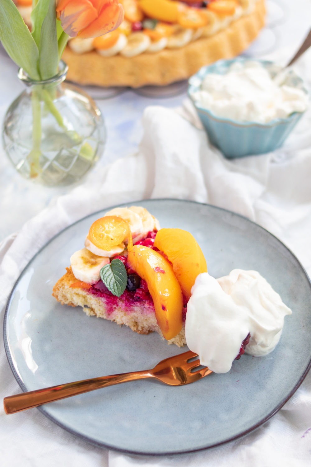 Obstkuchen backen: einfacher und schneller Obstkuchen mit Biskuitboden und Früchten deiner Wahl. Stück Obstkuchen mit Früchten und Sahne